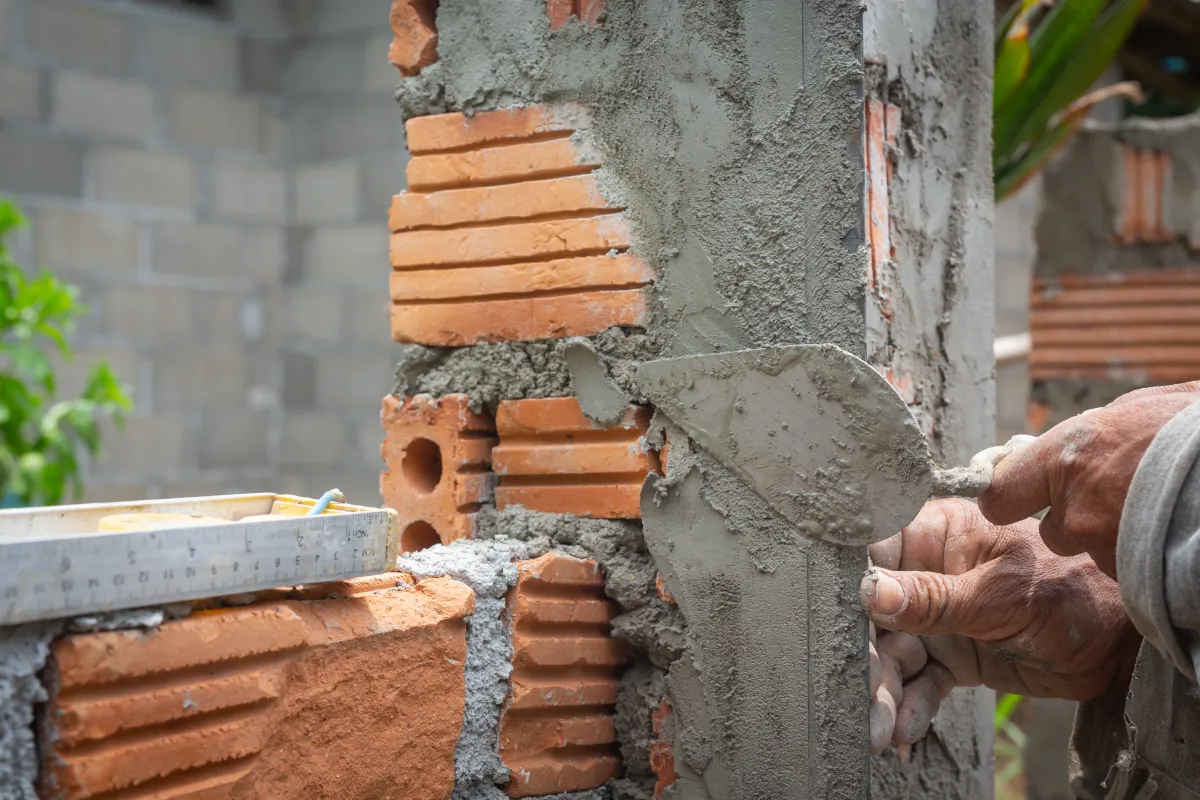 Albañil construyendo pared de ladrillos en obra de reforma